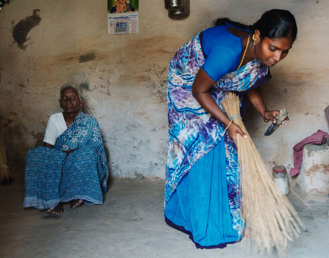 Mrs. Aarayi sits at home while her granddaughter Sharmila helps with chores.